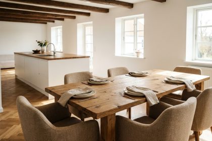 Grande table à manger familiale en chêne massif avec six chaises rembourrées dans une salle à manger ouverte aux tons chaleureux